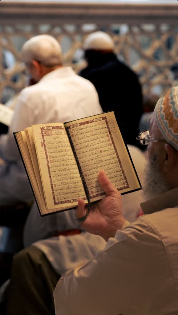 Elderly Muslim man reciting from an open copy of the Holy Quran