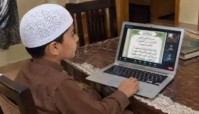 Young student in white topi learning Quran over live Zoom session with online tutor